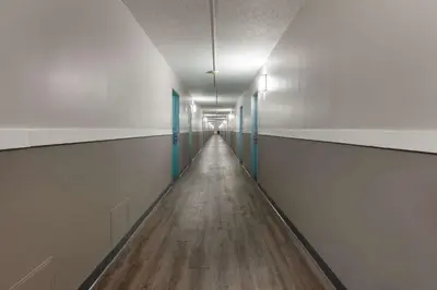 a long hallway with a long wooden floor and blue doors at Travelodge by Wyndham Cleveland Airport in Brook Park