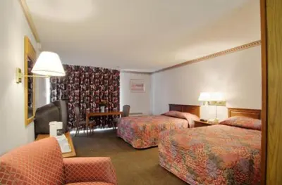 a hotel room with two beds and a chair at Travelodge by Wyndham Cleveland Airport in Brook Park