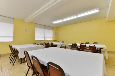 a room with white tables and chairs and yellow walls at Travelodge by Wyndham Cleveland Airport in Brook Park