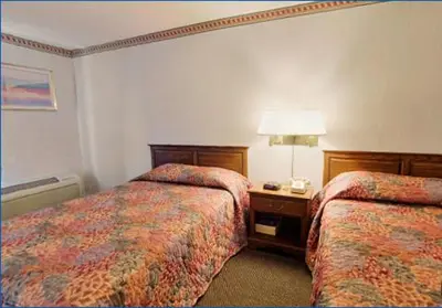 a hotel room with two beds and a table with a lamp at Travelodge by Wyndham Cleveland Airport in Brook Park