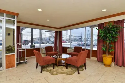 a living room with a table and chairs and windows at Travelodge by Wyndham Cleveland Airport in Brook Park