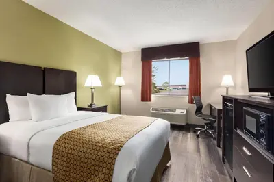 a hotel room with a bed and a television at Baymont by Wyndham Monroe in Monroe