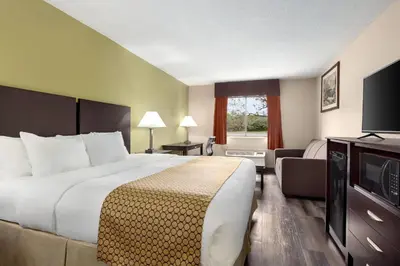 a hotel room with a large bed and a television at Baymont by Wyndham Monroe in Monroe