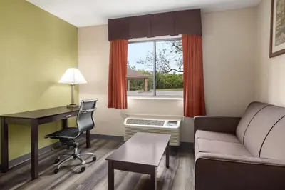 a living room with a desk and a couch and a table at Baymont by Wyndham Monroe in Monroe