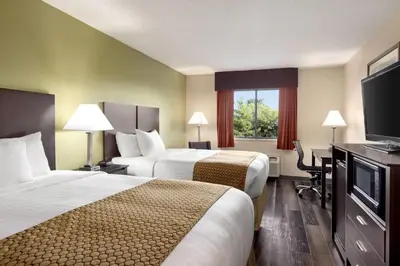 a hotel room with two beds and a flat screen tv at Baymont by Wyndham Monroe in Monroe
