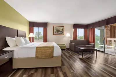 a hotel room with a large bed and a chair at Baymont by Wyndham Monroe in Monroe
