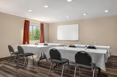 a conference room with tables and chairs and a whiteboard at Baymont by Wyndham Monroe in Monroe