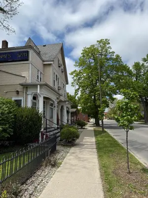 a white house with a fence next to a sidewalk at Historic LaSalle Downtown in Fort Wayne