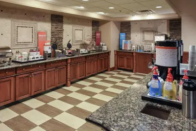 a kitchen with wooden cabinets and a man behind the counter at Hampton Inn & Suites Youngstown-Canfield in Canfield