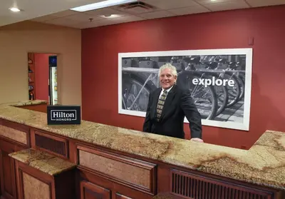 a man in a suit standing behind a counter at Hampton Inn & Suites Youngstown-Canfield in Canfield