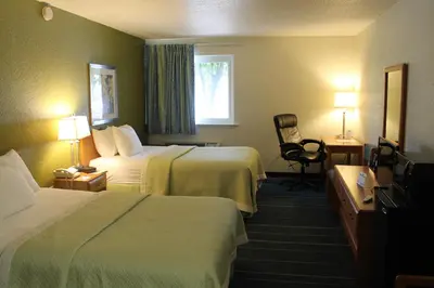 a hotel room with two beds and a television at Days Inn & Suites by Wyndham Bridgeport - Clarksburg in Bridgeport