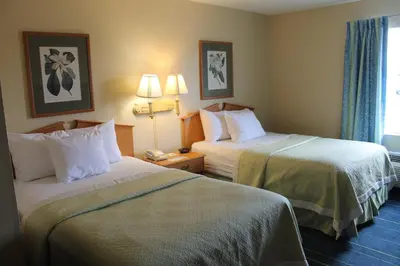 a hotel room with two beds and two lamps at Days Inn & Suites by Wyndham Bridgeport - Clarksburg in Bridgeport