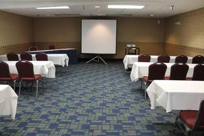 a conference room with tables and chairs and a screen at Days Inn & Suites by Wyndham Bridgeport - Clarksburg in Bridgeport