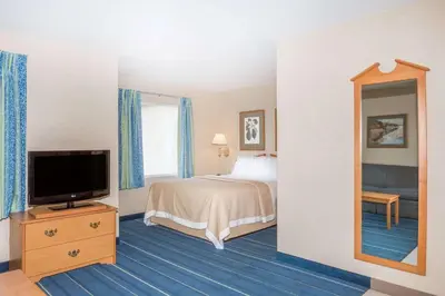a hotel room with a bed and a television at Days Inn & Suites by Wyndham Bridgeport - Clarksburg in Bridgeport