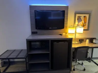 a room with a desk with a tv and a desk with a chair at Baymont by Wyndham Dayton North in Dayton