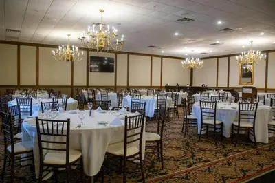 a banquet room with white tables and chairs and chandeliers at The Stables Inn & Suites in Salem