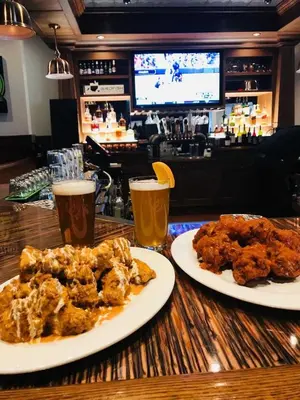 two plates of food and two glasses of beer on a bar at The Stables Inn & Suites in Salem