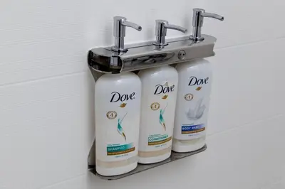 a rack with three bottles of deodorants on a wall at Holiday Inn Express - Charleston/Kanawha City by IHG in Charleston