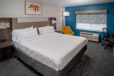 a hotel room with a large bed and a chair at Holiday Inn Express - Charleston/Kanawha City by IHG in Charleston