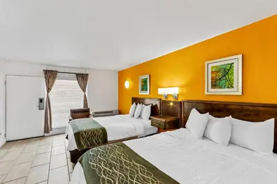 two beds in a hotel room with orange walls at Americas Best Value Inn & Suites Williamstown in Williamstown