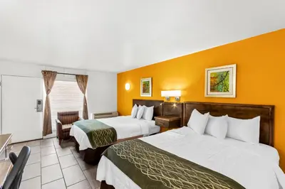 two beds in a hotel room with orange walls at Americas Best Value Inn & Suites Williamstown in Williamstown