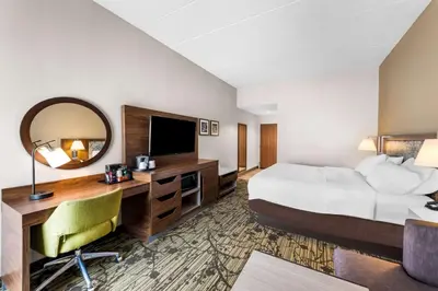 a hotel room with a bed and a desk with a mirror at Hampton Inn Dayton/Huber Heights in Huber Heights