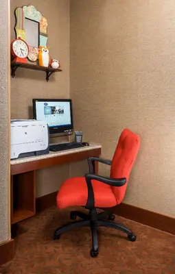 a red chair in front of a desk with a computer at Hampton Inn Mansfield/Ontario in Mansfield