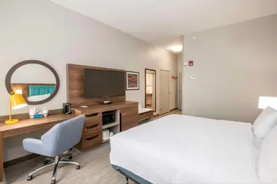 a hotel room with a bed and a desk with a television at Hampton Inn Dry Ridge in Dry Ridge