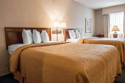 a hotel room with two beds with white pillows at Quality Inn Pittsburgh Airport in Oakdale