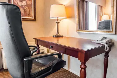 a desk with a phone and a chair in a room at Quality Inn Pittsburgh Airport in Oakdale