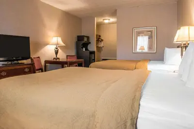 a hotel room with two beds and a flat screen tv at Quality Inn Pittsburgh Airport in Oakdale