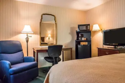 a hotel room with a bed and a chair and a desk at Quality Inn Pittsburgh Airport in Oakdale