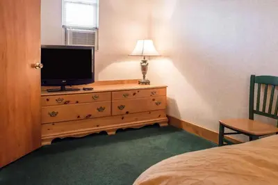 a bedroom with a dresser with a television and a bed at Quality Inn Pittsburgh Airport in Oakdale