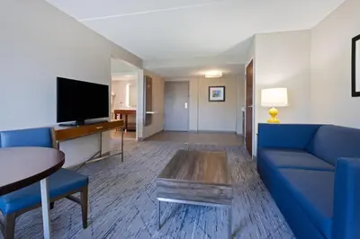a living room with a blue couch and a tv at Holiday Inn Express & Suites Cincinnati Riverfront by IHG in Covington