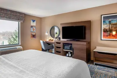 a hotel room with a bed and a flat screen tv at Hampton Inn Greenfield in Greenfield