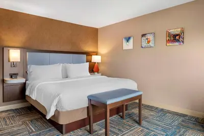 a hotel room with a bed and a stool at Hampton Inn Greenfield in Greenfield
