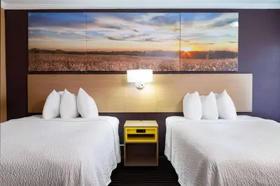 two beds in a hotel room with a painting on the wall at Days Inn by Wyndham Anderson IN in Anderson