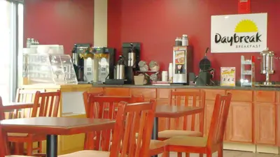 a restaurant with tables and chairs in front of a counter at Days Inn by Wyndham Anderson IN in Anderson