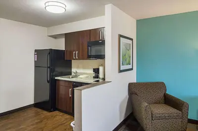 a kitchen with a refrigerator and a chair in a room at Suburban Studios Monaca - Pittsburgh in Monaca