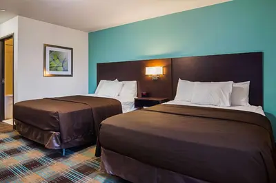 a hotel room with two beds and blue walls at Suburban Studios Monaca - Pittsburgh in Monaca