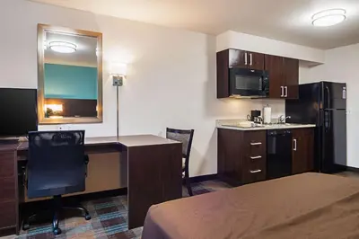 a hotel room with a bed and a desk and a kitchen at Suburban Studios Monaca - Pittsburgh in Monaca