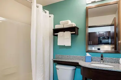 a bathroom with a toilet and a sink and a mirror at Suburban Studios Monaca - Pittsburgh in Monaca