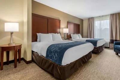 a hotel room with two beds and a chair at Comfort Suites Dayton-Wright Patterson in Dayton