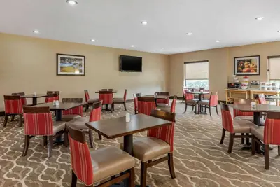 a restaurant with tables and chairs and a television at Comfort Suites Dayton-Wright Patterson in Dayton