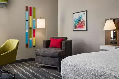 a hotel room with a chair and a bed at Hampton Inn Massillon in Massillon