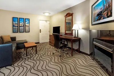 a hotel room with a desk and a living room at La Quinta Inn by Wyndham Sandusky near Cedar Point in Sandusky