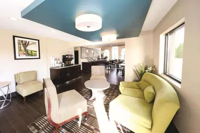 a living room with a couch and a table and chairs at La Quinta Inn by Wyndham Sandusky near Cedar Point in Sandusky