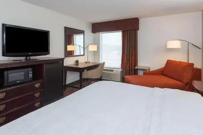 a hotel room with a bed and a flat screen tv at Hampton Inn Parkersburg/Mineral Wells in Mineralwells