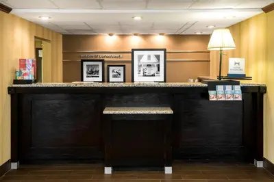 a bar in a hotel lobby with pictures on the wall at Hampton Inn Parkersburg/Mineral Wells in Mineralwells