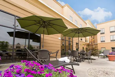 a patio with tables and chairs with umbrellas and flowers at Hampton Inn & Suites Springboro in Springboro